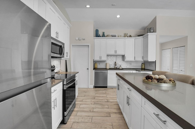9794 Ridgecreek Rd, Boca Raton, FL 33496 - kitchen featuring appliances with stainless steel finishes, a sink, dark countertops, white cabinetry, and recessed lighting