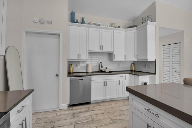 9794 Ridgecreek Rd, Boca Raton, FL 33496 - kitchen featuring stainless steel dishwasher, dark countertops, a sink, tasteful backsplash, and white cabinetry