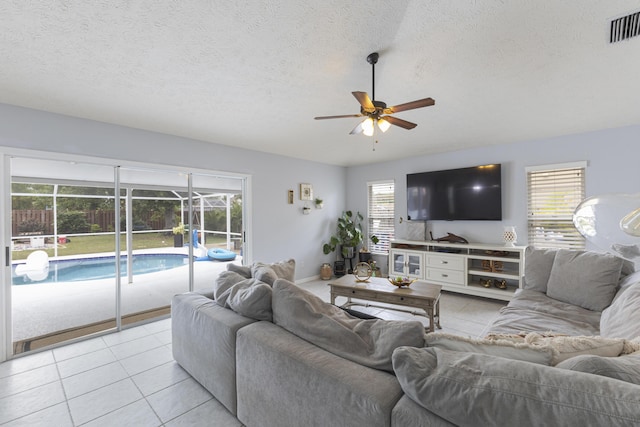 living area with ceiling fan, a sunroom, light tile patterned floors, a textured ceiling, and baseboards