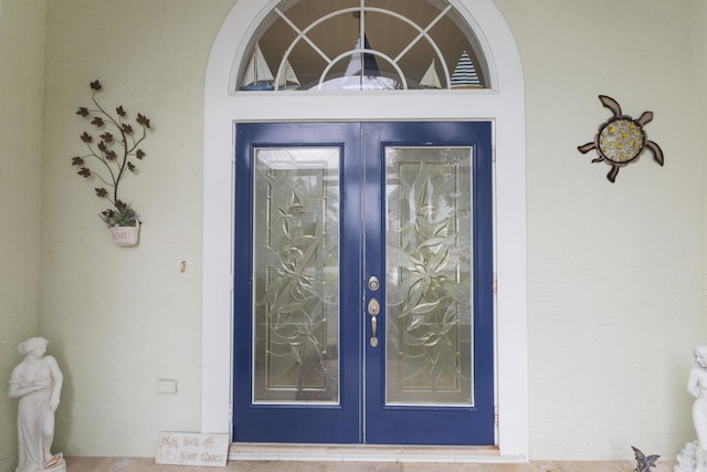 view of exterior entry featuring french doors and stucco siding