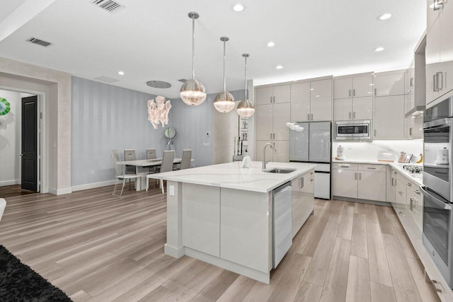 9333 Mountain Pine Grv, Boynton Beach, FL 33473 - kitchen with appliances with stainless steel finishes, a sink, light wood-type flooring, baseboards, and a kitchen island with sink