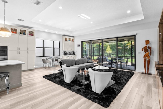 9333 Mountain Pine Grv, Boynton Beach, FL 33473 - living room featuring a tray ceiling, baseboards, light wood-style flooring, and recessed lighting