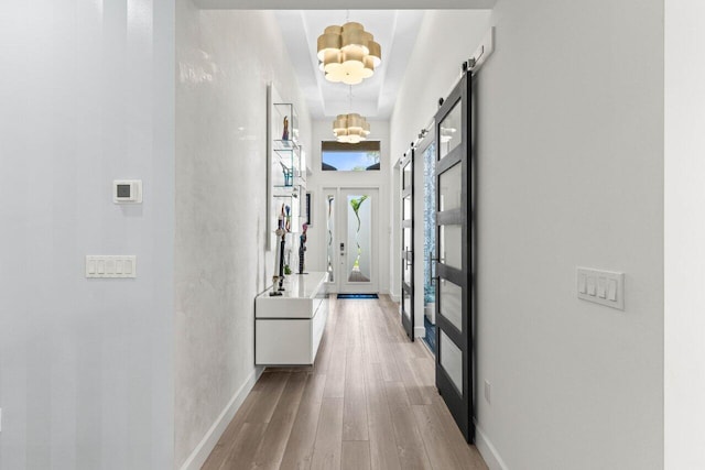 9333 Mountain Pine Grv, Boynton Beach, FL 33473 - corridor featuring wood finished floors, a barn door, a chandelier, and baseboards