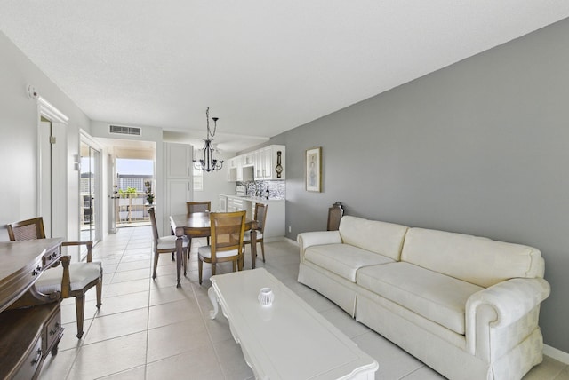 living room with a chandelier, light tile patterned flooring, and baseboards