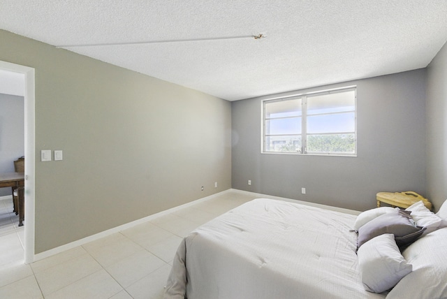 bedroom featuring a textured ceiling, baseboards, and light tile patterned floors