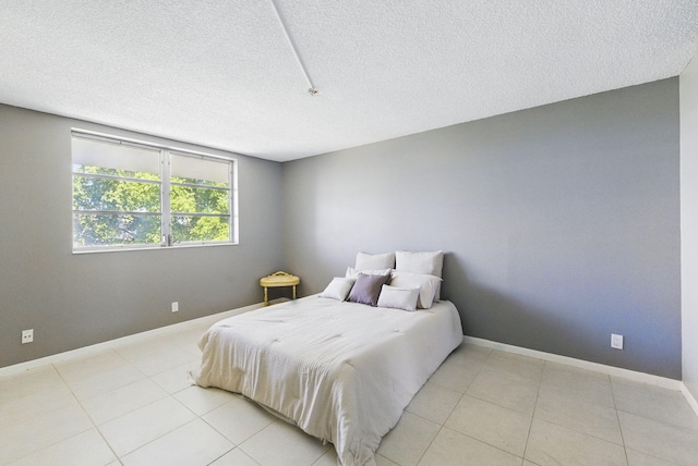 bedroom featuring a textured ceiling, light tile patterned floors, and baseboards