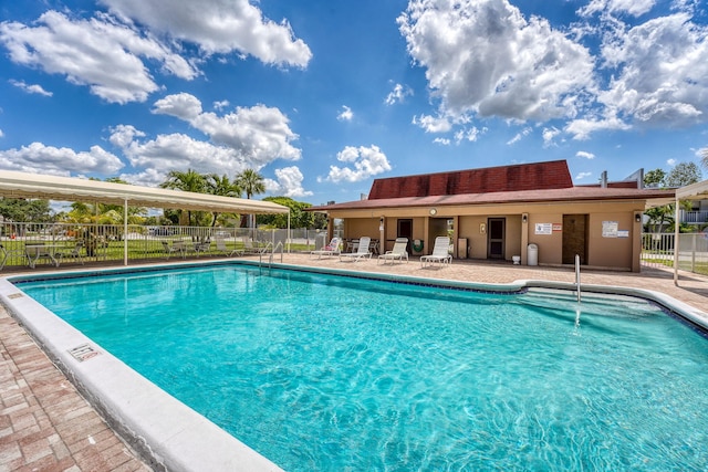 community pool featuring fence and a patio