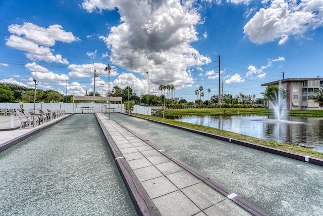 surrounding community featuring a game area, fence, and a water view
