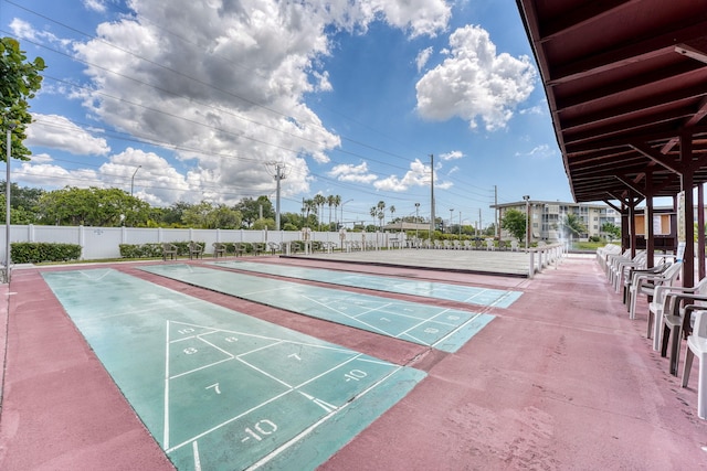 view of property's community featuring fence and shuffleboard