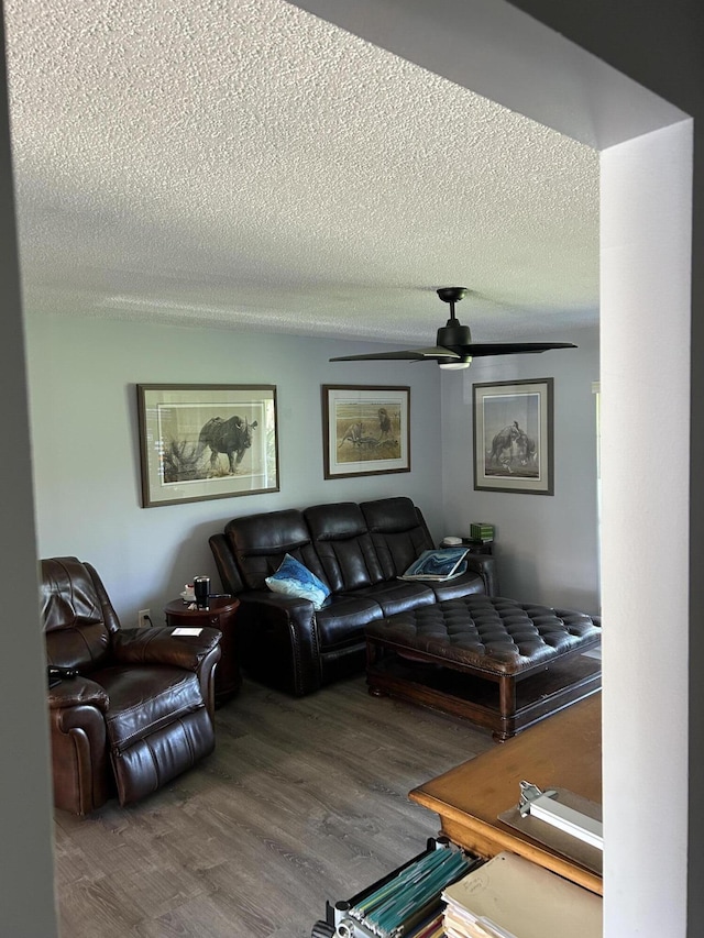 living room with a textured ceiling, wood finished floors, and ceiling fan