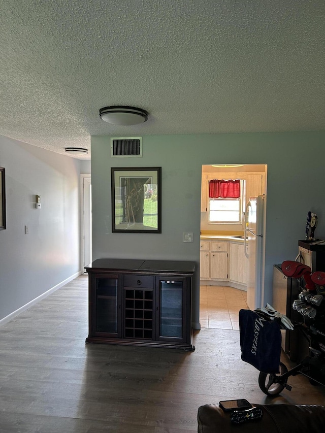 living room featuring a textured ceiling, light wood-style floors, and baseboards