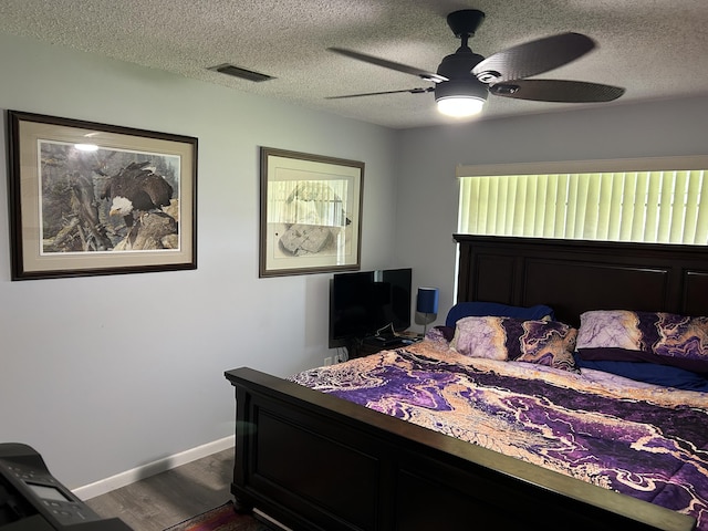 bedroom with dark wood-type flooring, a textured ceiling, baseboards, and a ceiling fan
