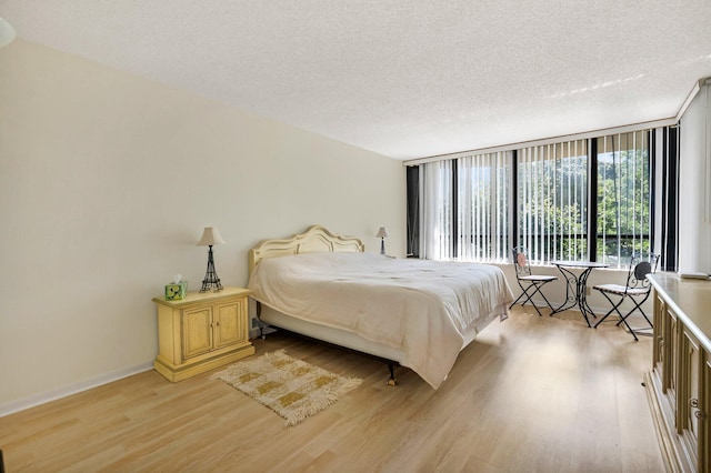 bedroom with light wood finished floors, a textured ceiling, and baseboards