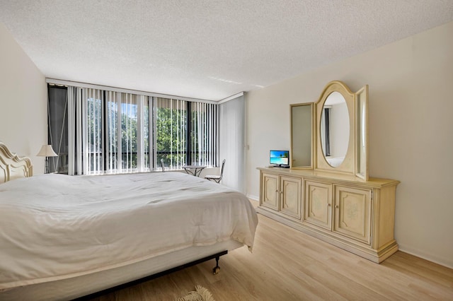 bedroom featuring light wood-style flooring, a textured ceiling, and floor to ceiling windows
