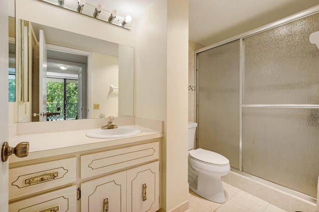 bathroom with toilet, tile patterned flooring, a stall shower, and vanity