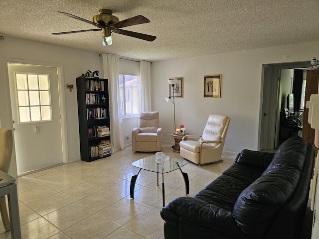 living room featuring ceiling fan, light tile patterned flooring, a textured ceiling, and baseboards