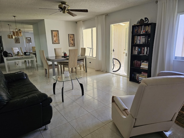 living area with a ceiling fan, a textured ceiling, and light tile patterned flooring