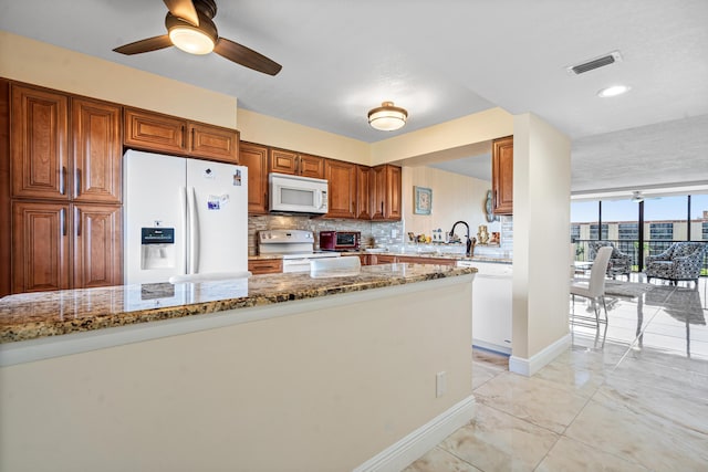 7290 Kinghurst Dr Unit 607, Delray Beach, FL 33446 - kitchen featuring white appliances, backsplash, brown cabinets, light stone countertops, and ceiling fan