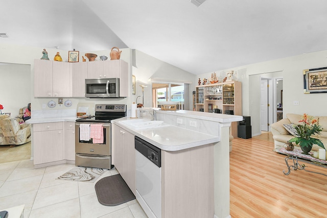 3204 SE Otis Ln, Port Saint Lucie, FL 34984 - kitchen featuring appliances with stainless steel finishes, a sink, a peninsula, light countertops, and lofted ceiling