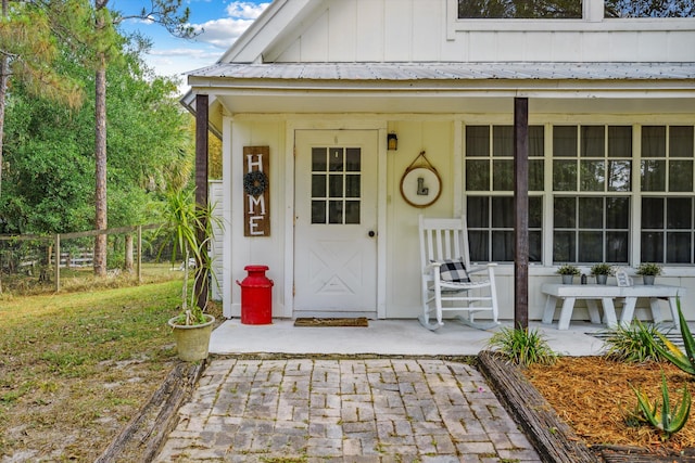 12389 186th St N, Jupiter, FL 33478 - entrance to property featuring board and batten siding, fence, metal roof, and covered porch