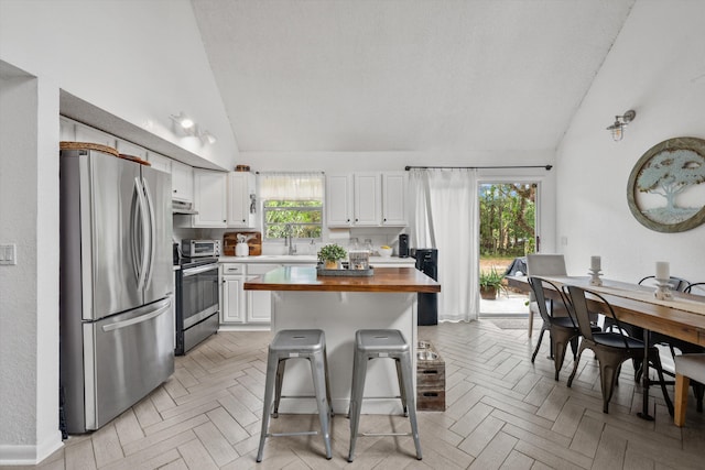 12389 186th St N, Jupiter, FL 33478 - kitchen featuring appliances with stainless steel finishes, wooden counters, a sink, white cabinetry, and a kitchen breakfast bar