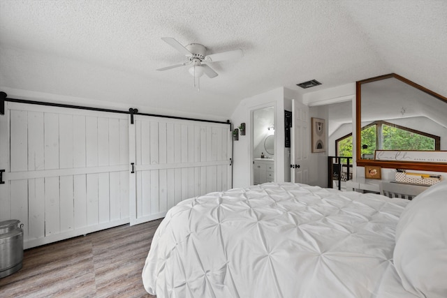 12389 186th St N, Jupiter, FL 33478 - bedroom with wood finished floors, lofted ceiling, a barn door, a textured ceiling, and ceiling fan