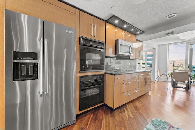 901 E Camino Real Unit 5C, Boca Raton, FL 33432 - kitchen with stainless steel appliances, dark wood finished floors, a textured ceiling, and brown cabinetry