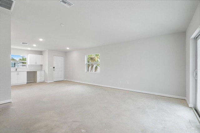 unfurnished living room with recessed lighting, concrete flooring, and baseboards