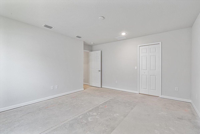 spare room featuring baseboards, a textured ceiling, and recessed lighting
