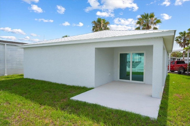 back of property with a patio area, a lawn, and stucco siding
