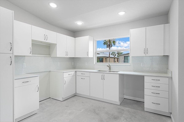 kitchen featuring a sink, unfinished concrete flooring, decorative backsplash, white cabinets, and recessed lighting