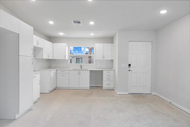 kitchen featuring white cabinets, backsplash, recessed lighting, unfinished concrete flooring, and light countertops