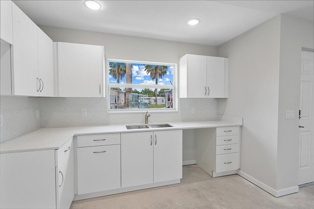 kitchen featuring a sink, concrete flooring, white cabinets, light countertops, and recessed lighting
