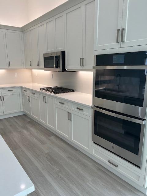 kitchen featuring appliances with stainless steel finishes, light wood-style flooring, light countertops, and white cabinets