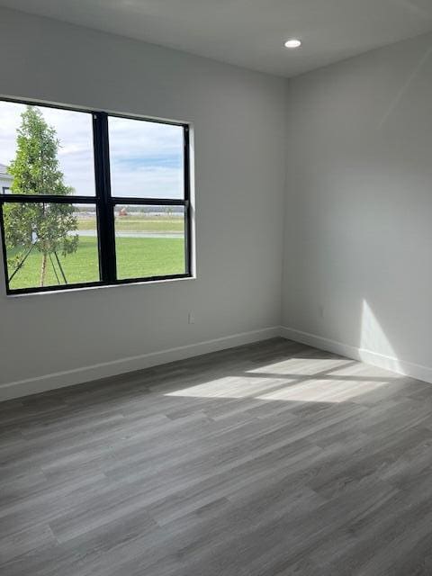 empty room featuring baseboards, wood finished floors, and recessed lighting