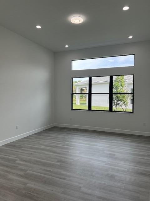 unfurnished room featuring recessed lighting, wood finished floors, and baseboards