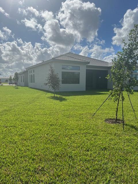 back of house featuring a yard and stucco siding