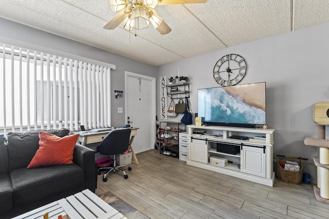 home office featuring light wood-style floors, a ceiling fan, and a textured ceiling