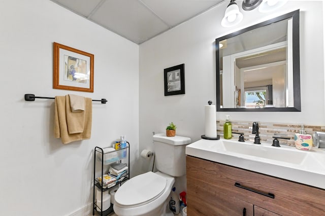 half bathroom with backsplash, toilet, and vanity