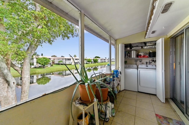 clothes washing area with separate washer and dryer, a water view, and light tile patterned floors