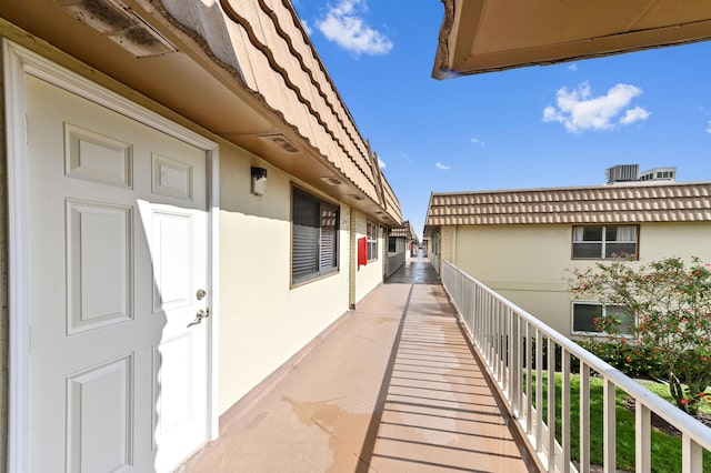 view of side of home featuring stucco siding, mansard roof, and a balcony