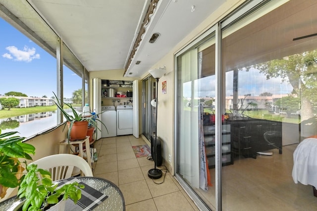 sunroom / solarium with washer and clothes dryer, tile patterned floors, and a water view