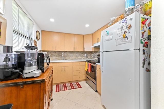 kitchen featuring freestanding refrigerator, stainless steel electric range, under cabinet range hood, a sink, and light brown cabinets