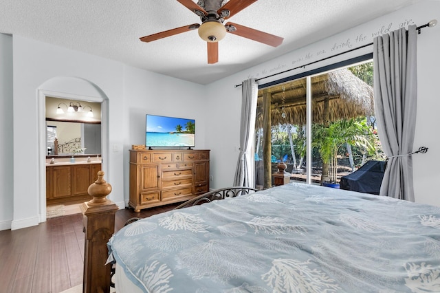bedroom featuring access to exterior, dark wood-type flooring, connected bathroom, a textured ceiling, and ceiling fan