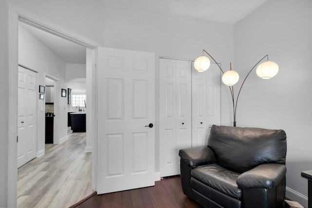 living area with arched walkways and wood finished floors