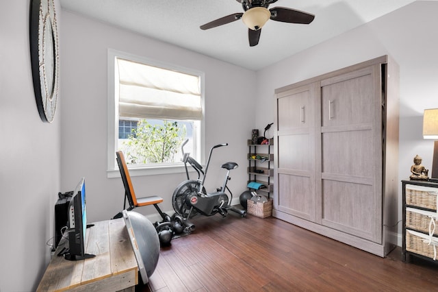 exercise room with a ceiling fan, dark wood finished floors, and baseboards