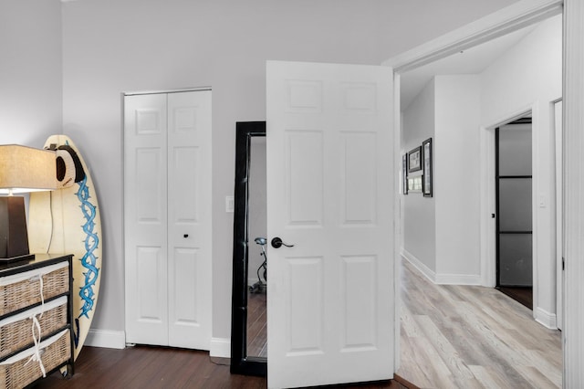 unfurnished bedroom featuring a closet, dark wood-style flooring, and baseboards