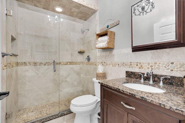 bathroom featuring vanity, toilet, tile walls, and a stall shower