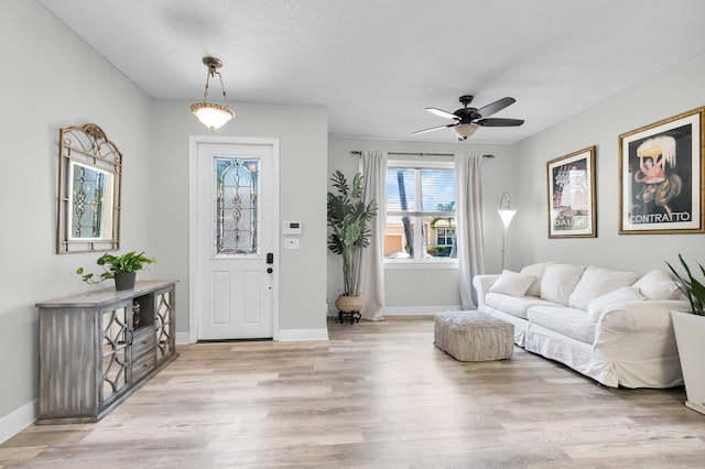 entrance foyer with light wood finished floors, ceiling fan, baseboards, and a textured ceiling