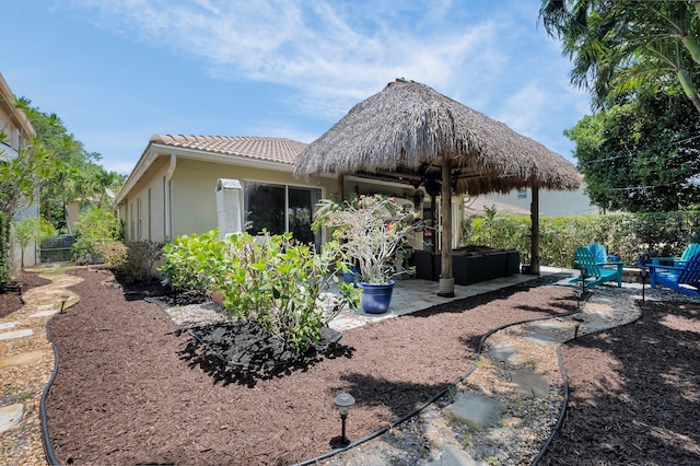 rear view of house with a tile roof, stucco siding, a patio, and fence